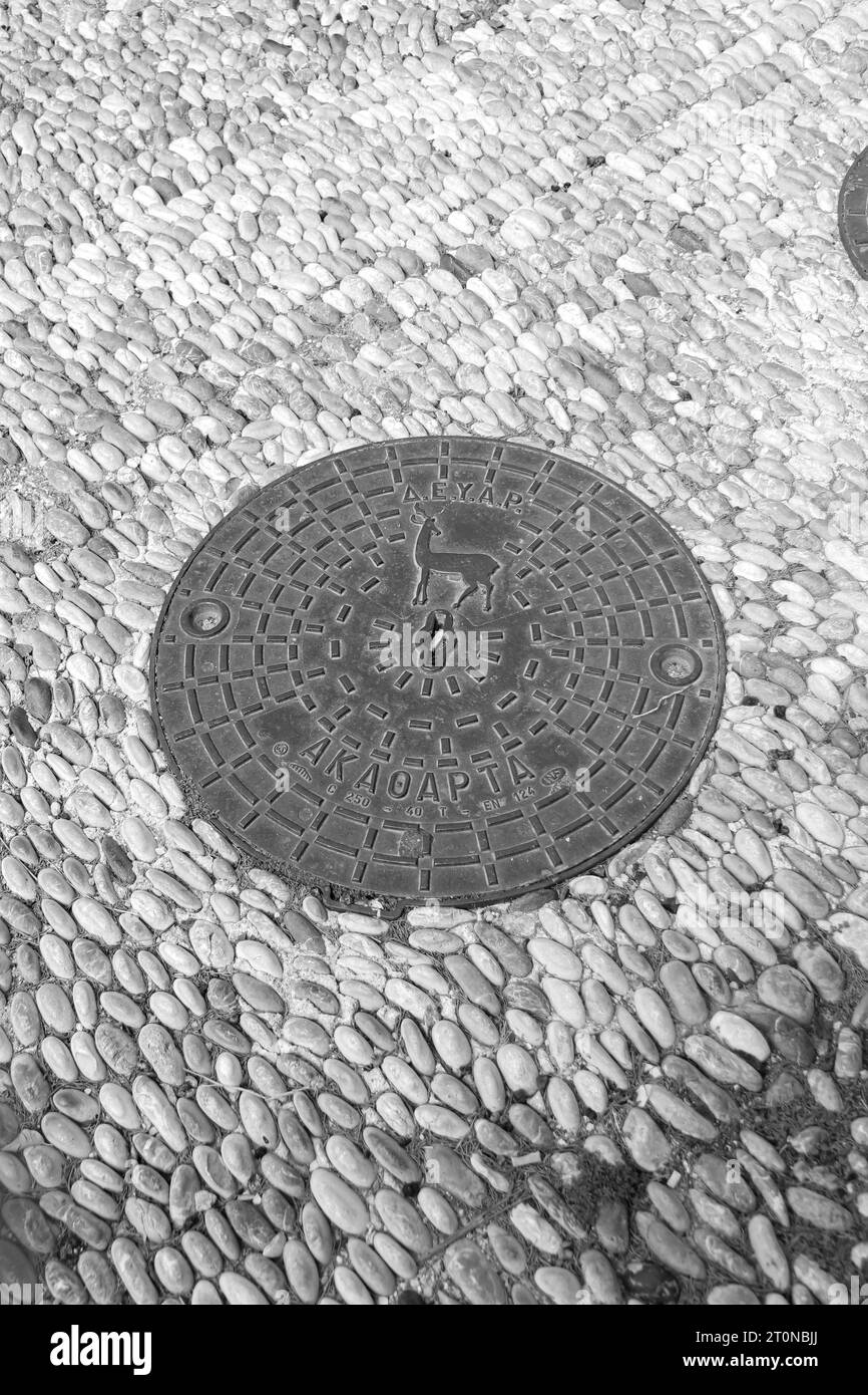Couvercle rond de trou d'homme, une plaque amovible recouvrant une ouverture dans le sol conçue pour l'Acropole de Rhodes en noir et blanc Banque D'Images