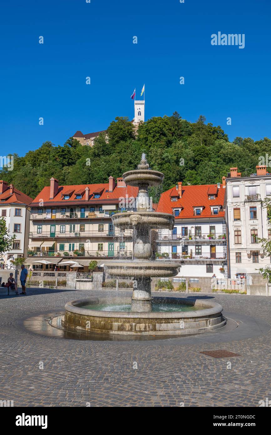 Ljubljana, Slovénie - 13 juillet 2022 : Fontaine sur la nouvelle place (Novi Trg) et vue sur la vieille ville et la colline du château dans la capitale. Banque D'Images