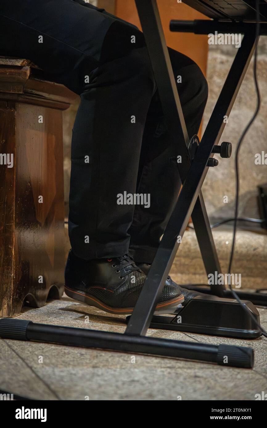 Image d'un pied d'homme utilisant la pédale de sustain sur le clavier du piano tout en jouant de la musique. Détail du support du clavier et de la pédale de sustain dans l'image. Banque D'Images