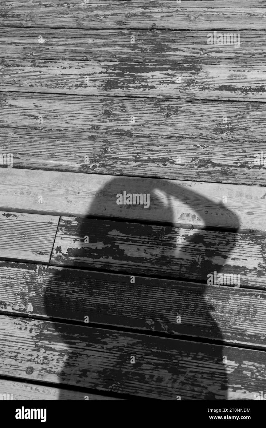 Personne tenant la caméra silhouette reflet du soleil sur la terrasse en bois en noir et blanc Banque D'Images