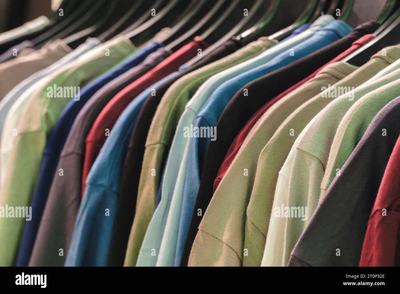 rangée de nombreux t-shirts frais en coton nouveau tissu dans des couleurs arc-en-ciel colorées accrochés sur le rail de vêtements en wrdrobe. Banque D'Images