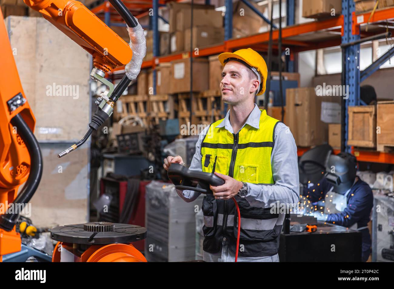 Homme d'ingénieur moderne intelligent utilisant la technologie de robot moderne. Installation de bras de soudage robotisé dans le processus de production d'automatisation en usine Banque D'Images