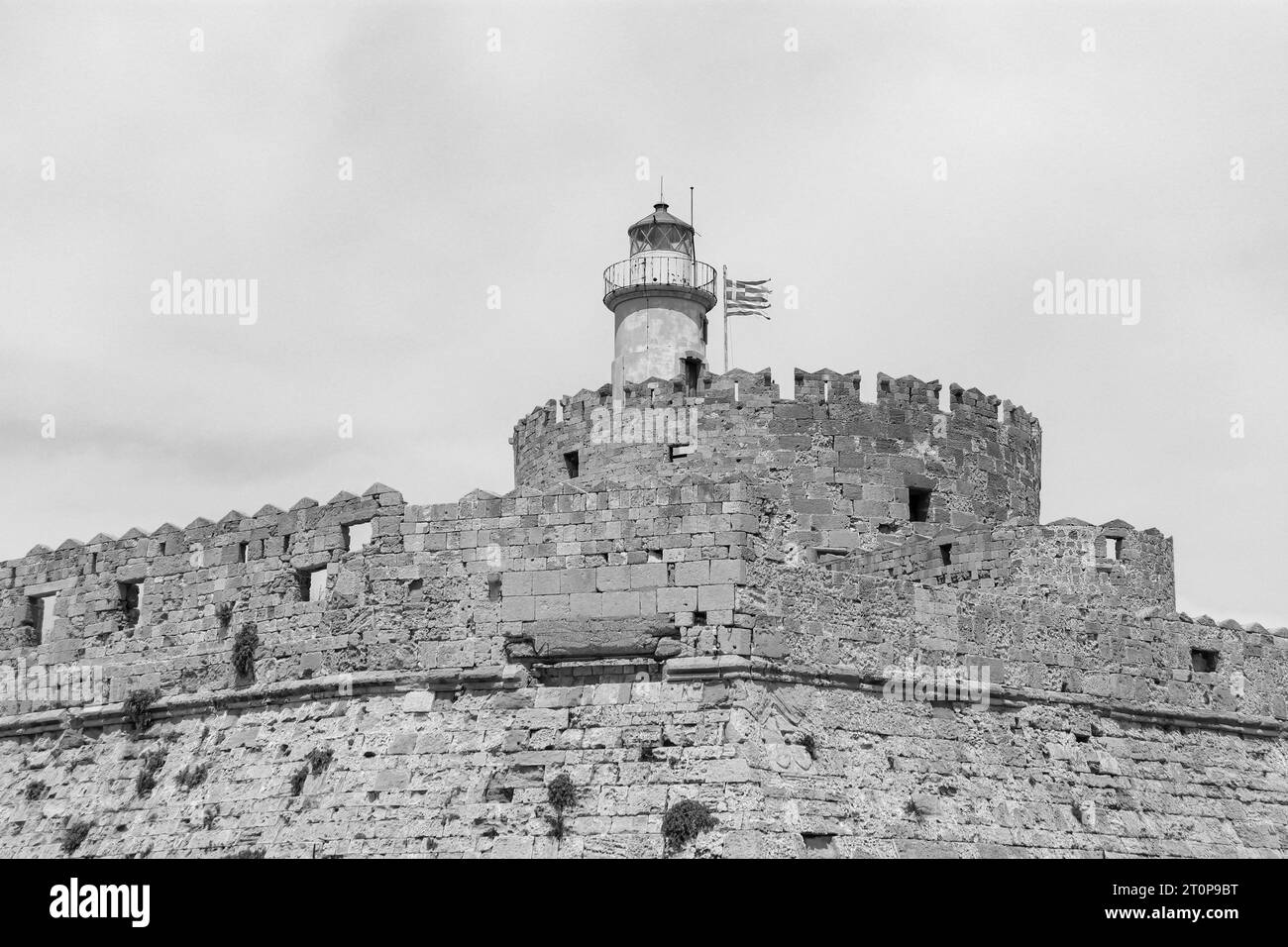 Gros plan de la tour ronde de la forteresse Saint-Nicolas avec phare et drapeau national de la Grèce en noir et blanc Banque D'Images