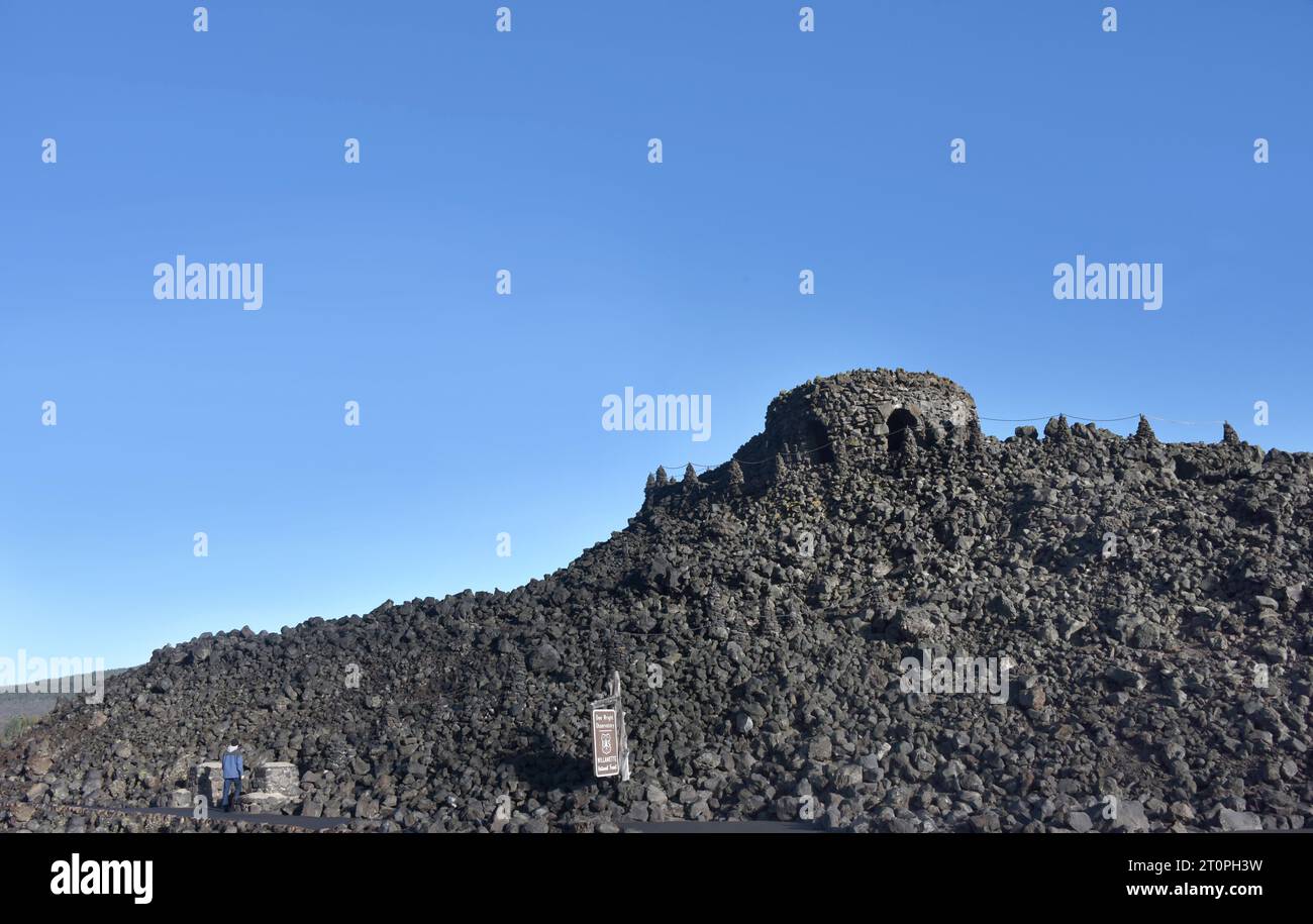 Le visiteur, en manteau bleu, monte des marches de lave jusqu'à l'observatoire Dee Wright. Il se trouve au sommet d'un champ de lave sur le McKenzie Pass, dans le centre de l'Oregon. Banque D'Images