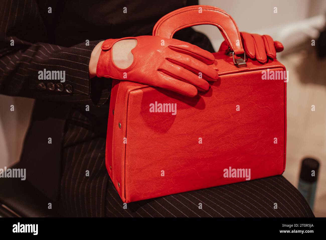 Mains féminines dans des gants en cuir tenant un sac à main rouge vif classique. Photo de mode Banque D'Images