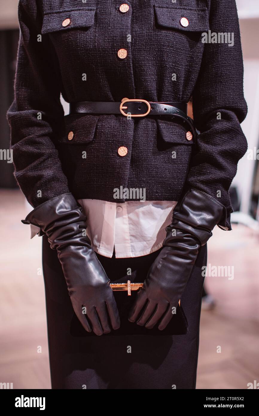 Détails de mode d'une veste noire élégante, ceinture en cuir, gants et pochette en velours classique. Mannequin posant sur les coulisses Banque D'Images