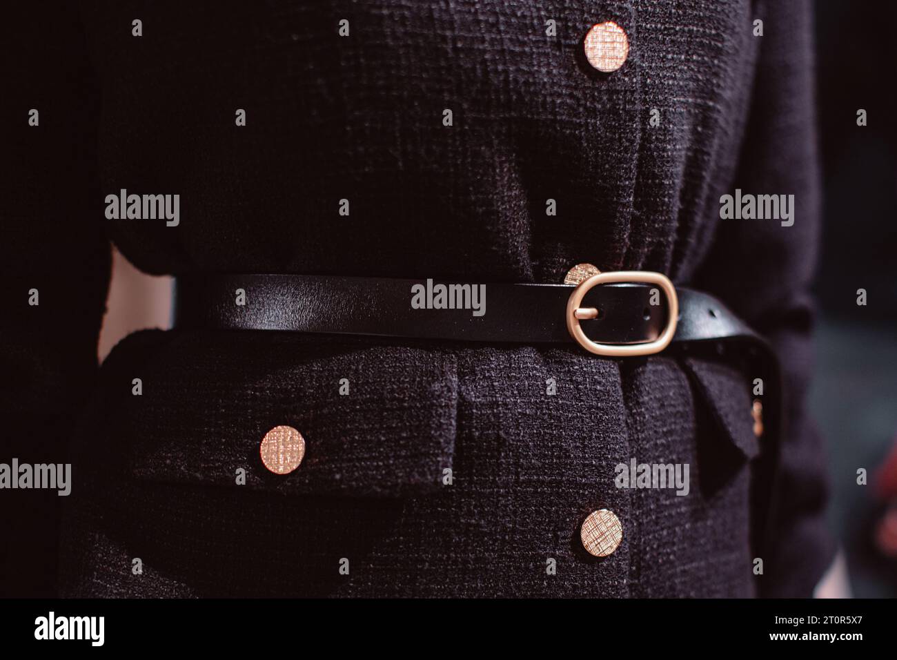 Détails de mode d'une veste noire élégante, ceinture en cuir et boutons dorés. Banque D'Images