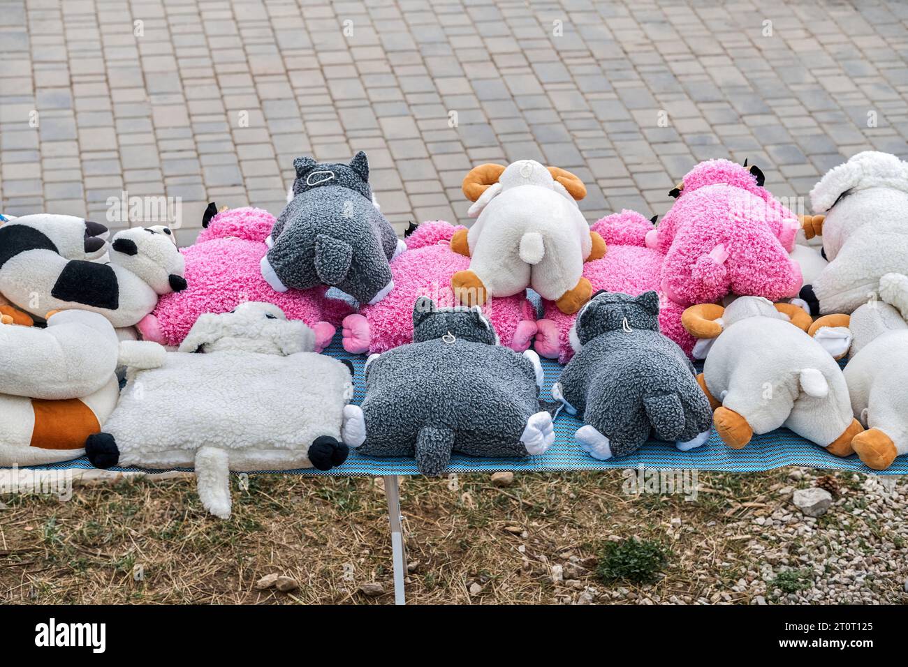 Jouets en peluche drôles empilés sur l'affichage simple sur la rue de la ville. Articles souvenirs faits à la main vendus sur la place de la ville. Petite boutique pour touriste en plein air Banque D'Images