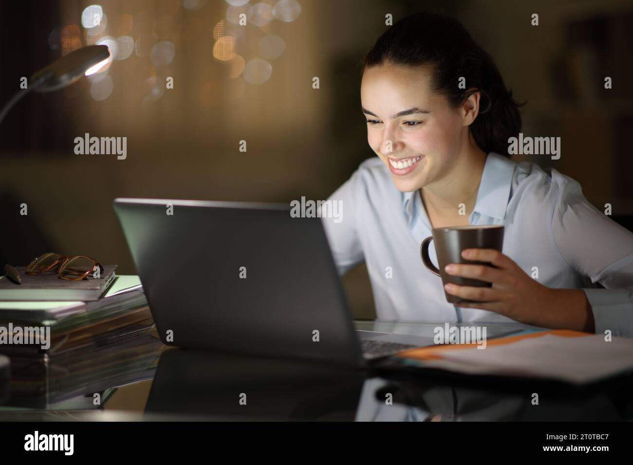 Heureuse femme d'affaires travaillant tard dans la nuit à la maison Banque D'Images