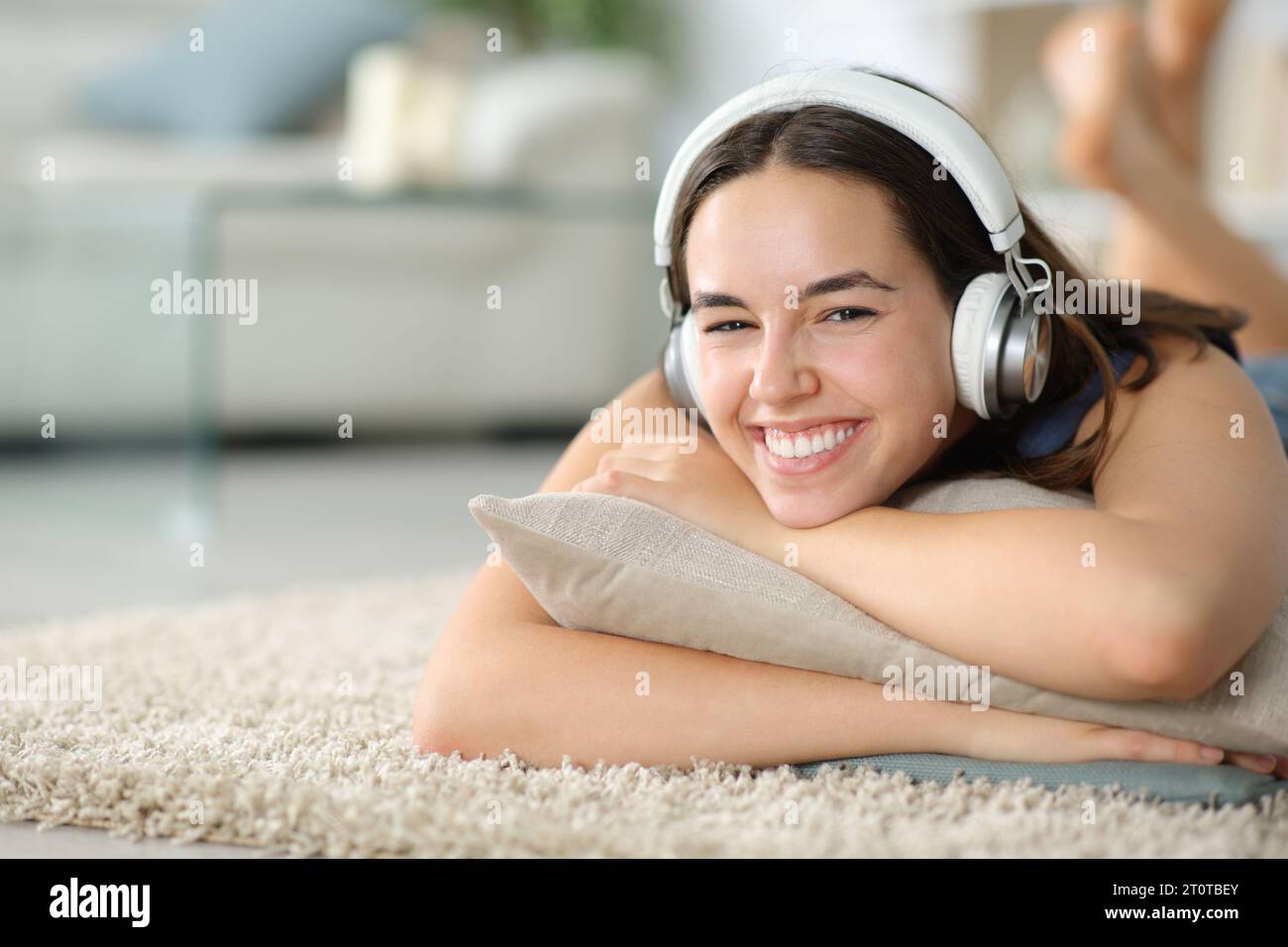 Femme heureuse te regarde porter un casque couché sur le sol à la maison Banque D'Images