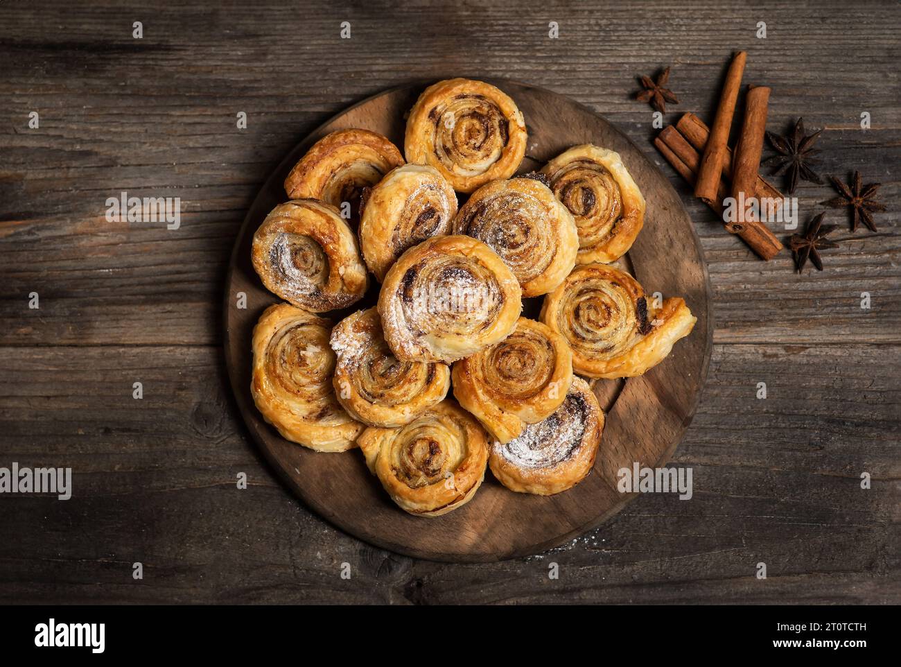 Petits pains à la cannelle sucrés et croustillants fraîchement cuits au four. Sur une assiette en bois, avec du sucre en poudre Banque D'Images