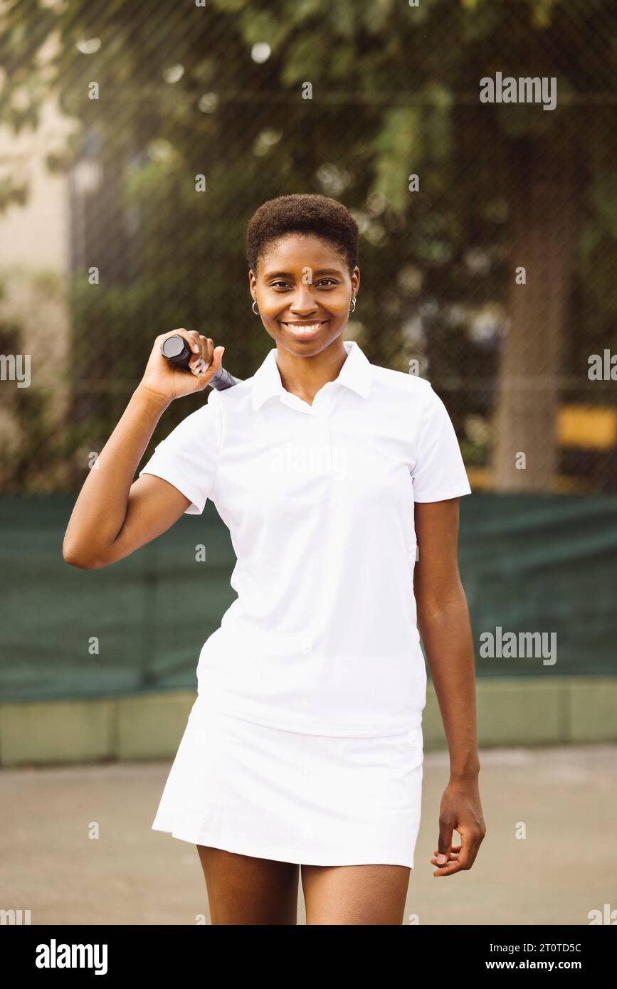 Portrait d'une jeune belle femme avec des vêtements de tennis et raquette dans un court de tennis prêt à jouer un jeu. Banque D'Images