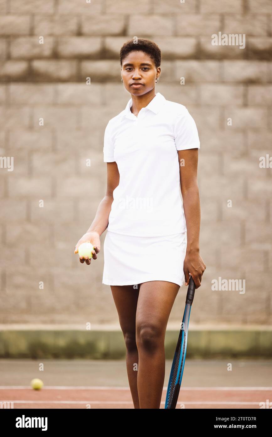 Portrait d'une jeune belle femme avec des vêtements de tennis et raquette dans un court de tennis prêt à jouer un jeu. Banque D'Images