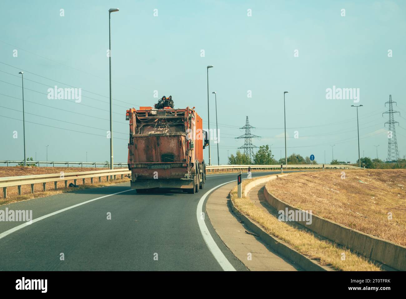 Camion poubelle orange sur autoroute, vue arrière avec mise au point sélective Banque D'Images
