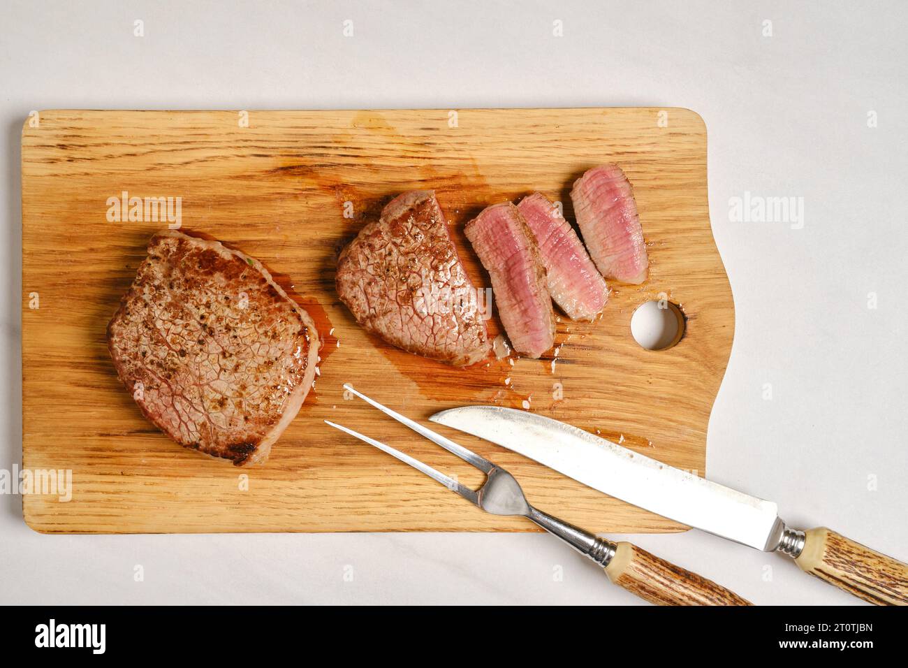 Vue de dessus de steak de bœuf juteux moyen rare sur planche à découper en bois coupé sur tranches Banque D'Images