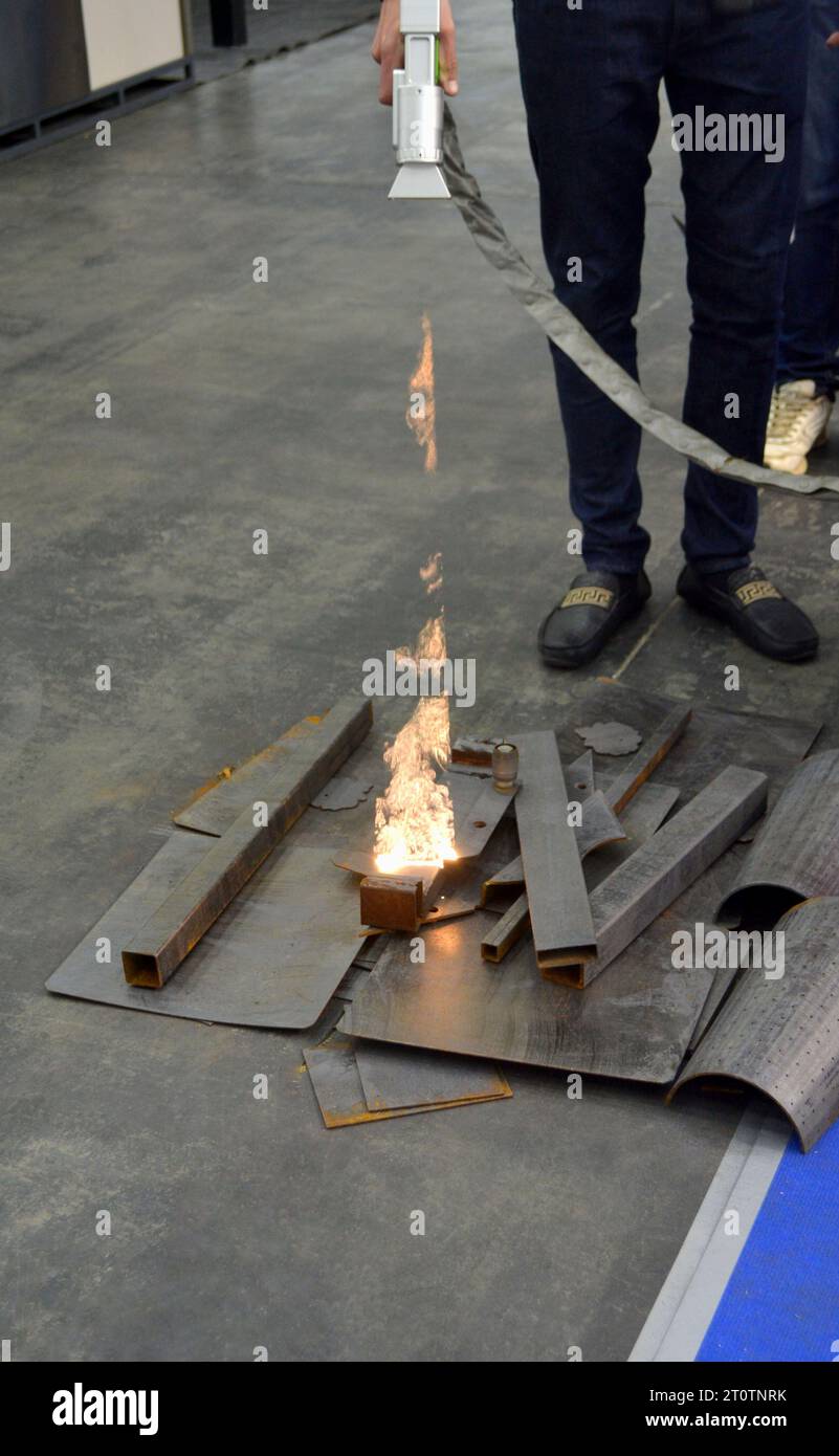 Nettoyage laser de métal. Enlèvement industriel de la rouille de la surface métallique avec faisceau laser. Homme nettoyant la surface de la corrosion avec la machine de nettoyage de métal laser. Rouille de nettoyage laser industriel du métal. Banque D'Images