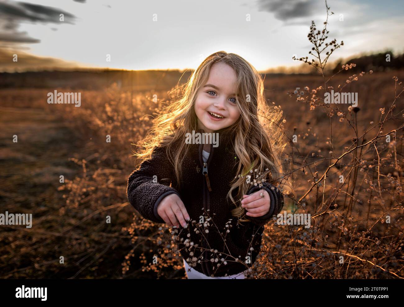 Heureuse jeune fille souriant dans le champ de fleurs à l'automne Banque D'Images