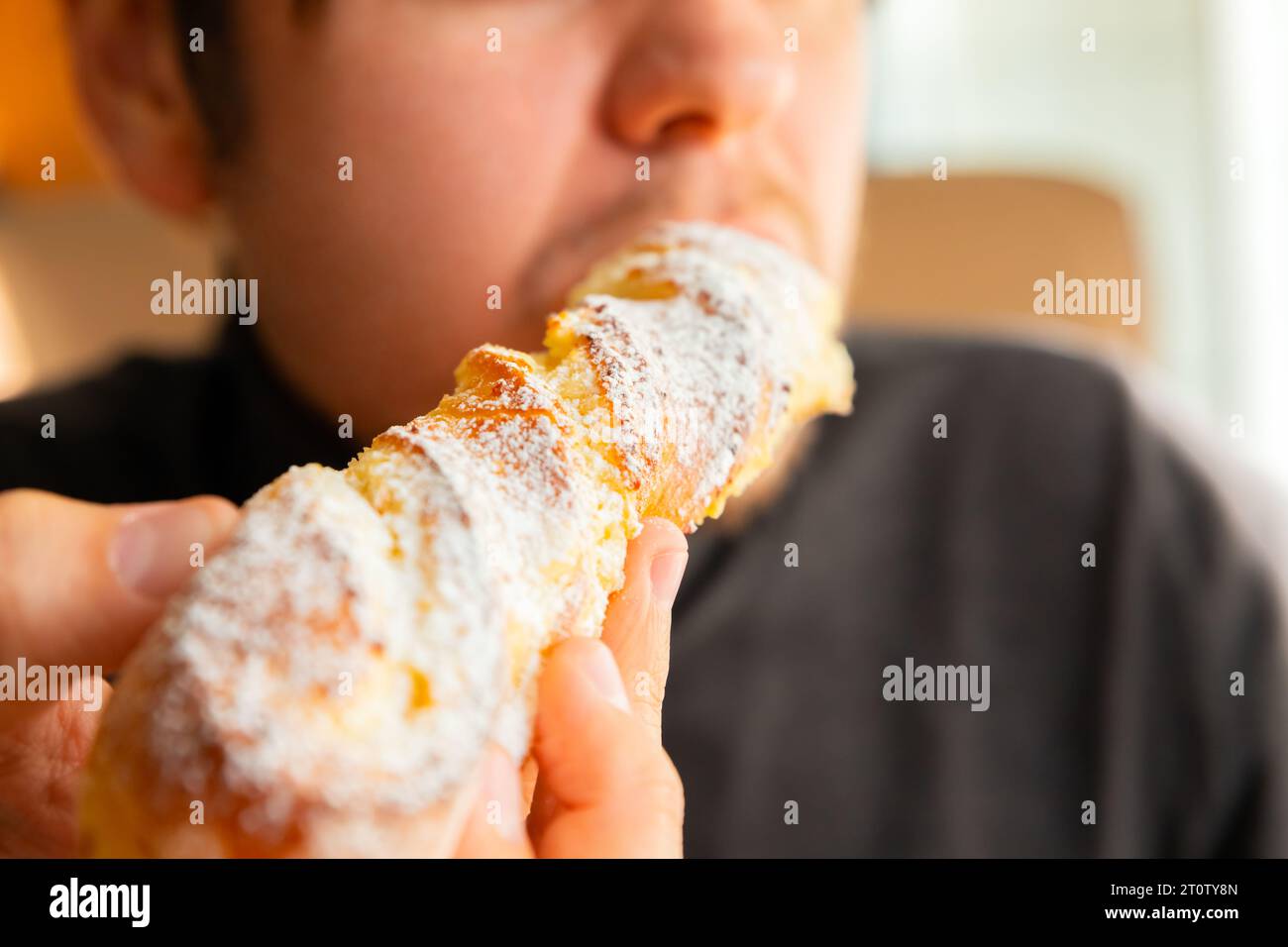 L'homme mange de la pâtisserie sucrée fraîchement longue au four au café boulangerie. Dessert sucré. Petit déjeuner dans un café confortable. Gros plan Banque D'Images