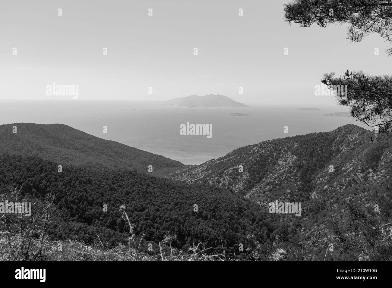 Vue côtière en noir et blanc d'une île Makri, l'une des Echinades, dans le groupe des îles Ioniennes vu de l'île de Rhodes Banque D'Images