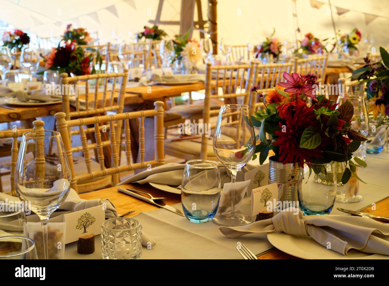 Chapiteau de mariage décoré et prêt pour les invités à arriver. Tables, chaises, fleurs et décors. Une conception rustique de tipi de tente. Banque D'Images
