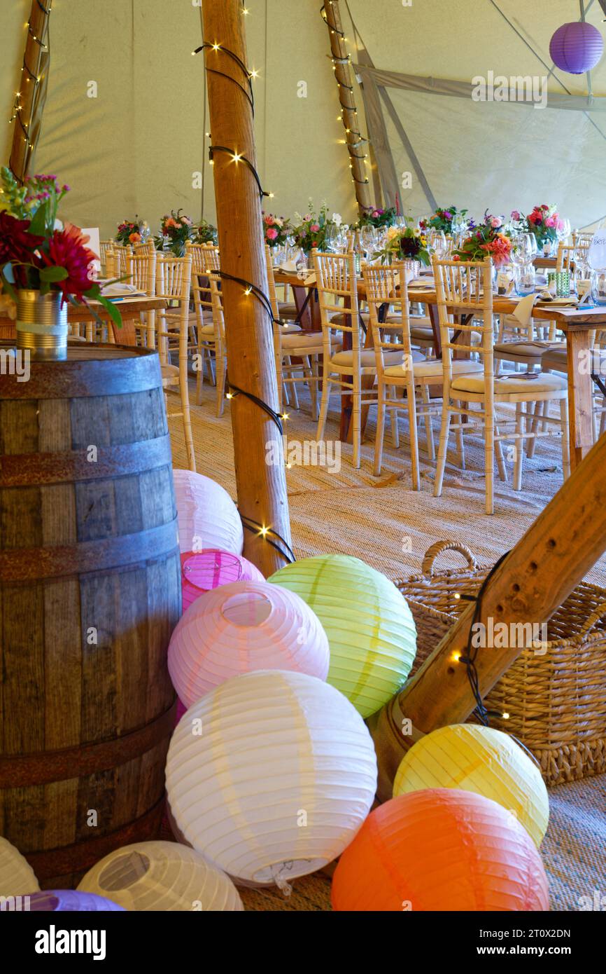 Chapiteau de mariage décoré et prêt pour les invités à arriver. Tables, chaises, fleurs et décors. Une conception rustique de tipi de tente. Banque D'Images