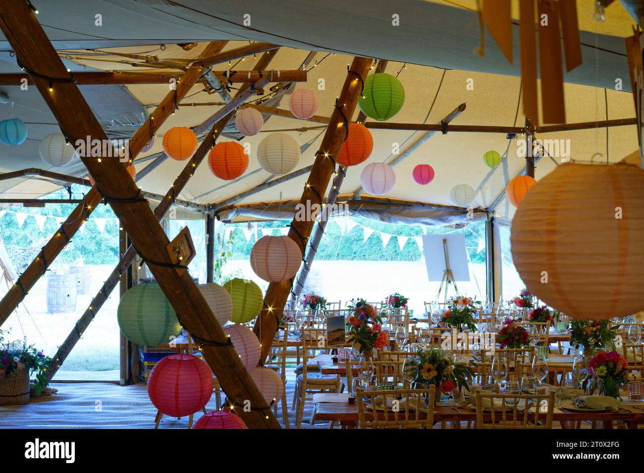 Chapiteau de mariage décoré et prêt pour les invités à arriver. Tables, chaises, fleurs et décors. Une conception rustique de tipi de tente. Banque D'Images