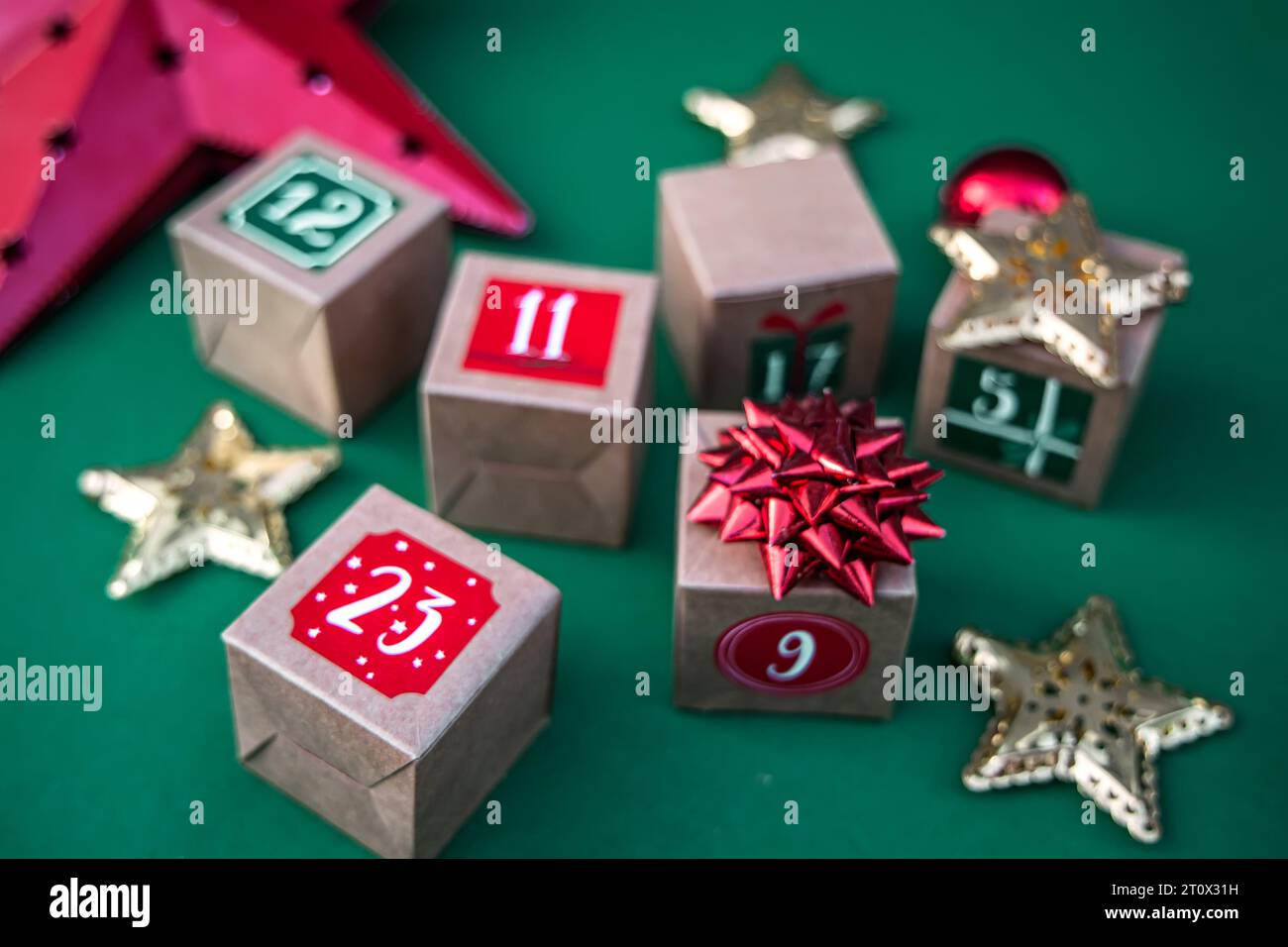 Calendrier de l'Avent artisanal : cubes de papier kraft avec des chiffres sur un fond vert vibrant. Adoptez la tradition des fêtes Banque D'Images