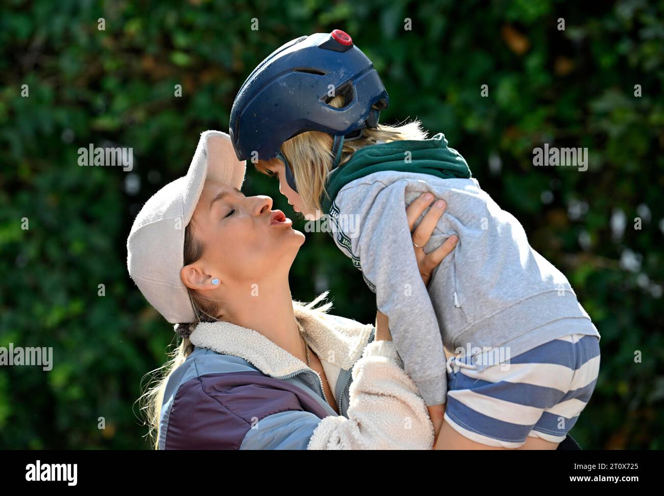 Mère, femme, blonde, casquette de baseball, baisers garçon avec casque, 5 ans, blonde, Stuttgart, Baden-Wuerttemberg, Allemagne Banque D'Images