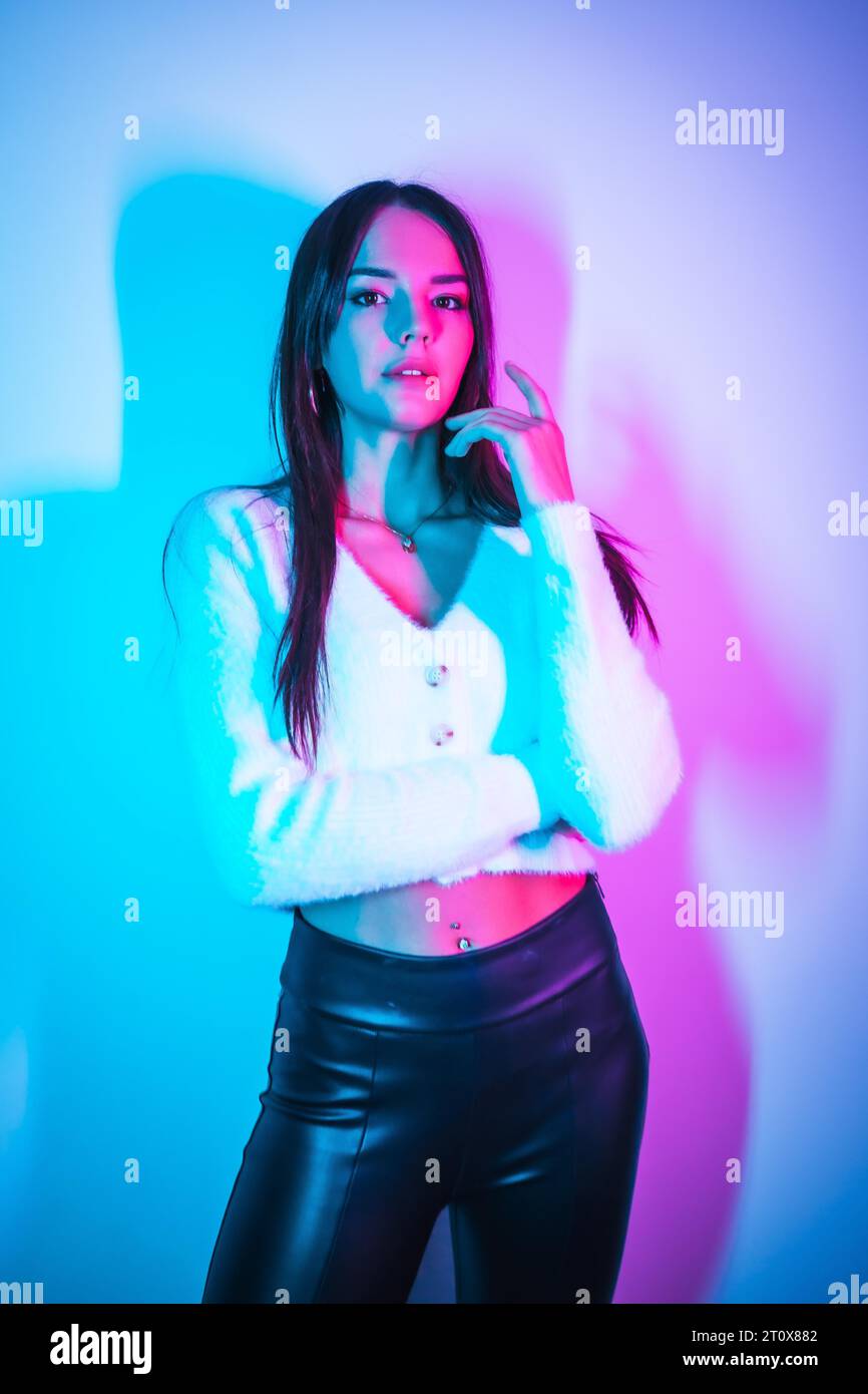 Style de vie de fête dans une boîte de nuit avec des néons bleus roses, portrait d'une jeune caucasienne brune s'amusant Banque D'Images