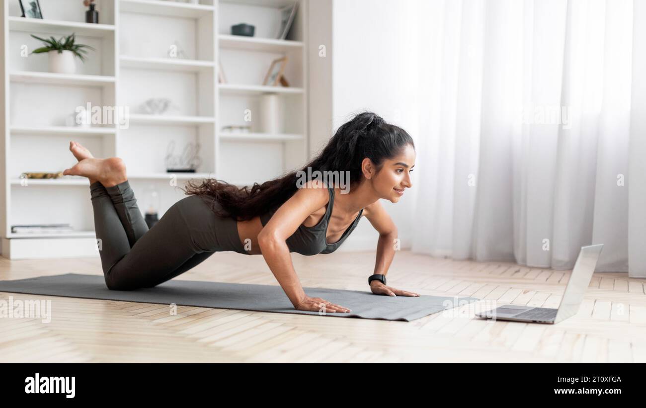 Jeune femme orientale sportive motivée s'exerçant à la maison Banque D'Images