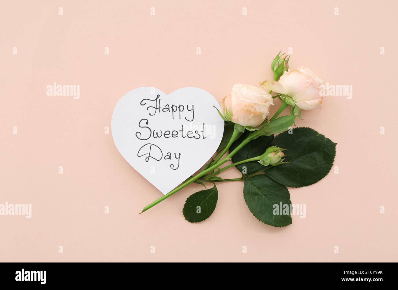 Carte avec texte HAPPY SWEETEST DAY et roses sur fond beige Banque D'Images