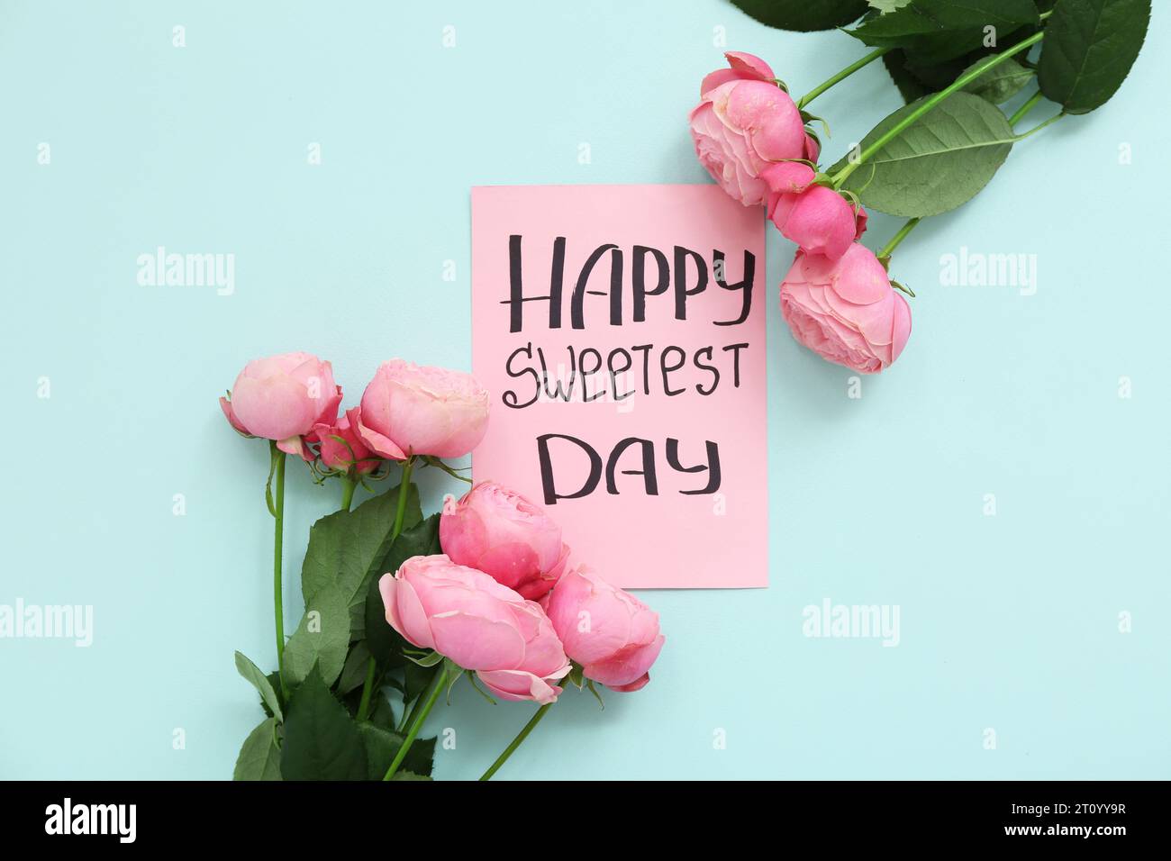 Carte avec texte HAPPY SWEETEST DAY et roses sur fond bleu Banque D'Images