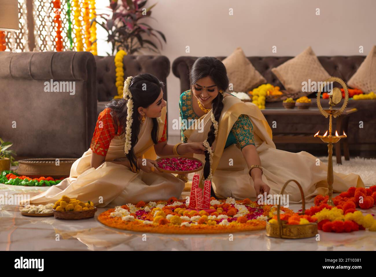 Femmes du sud de l'Inde en saree blanc décorant le sol avec des fleurs pour célébrer Onam Banque D'Images