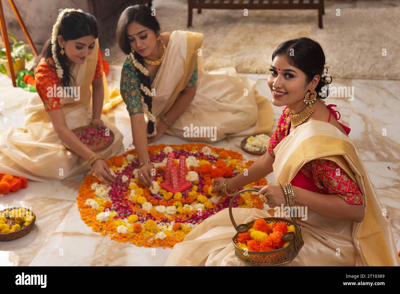 Femmes indiennes du Sud dans les vêtements traditionnels décorant le sol avec des fleurs ensemble pour célébrer Onam Banque D'Images
