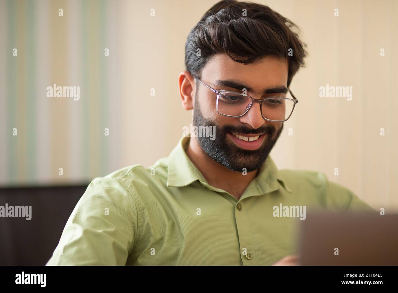 Portrait rapproché d'un jeune homme travaillant avec un ordinateur portable dans son bureau à domicile Banque D'Images