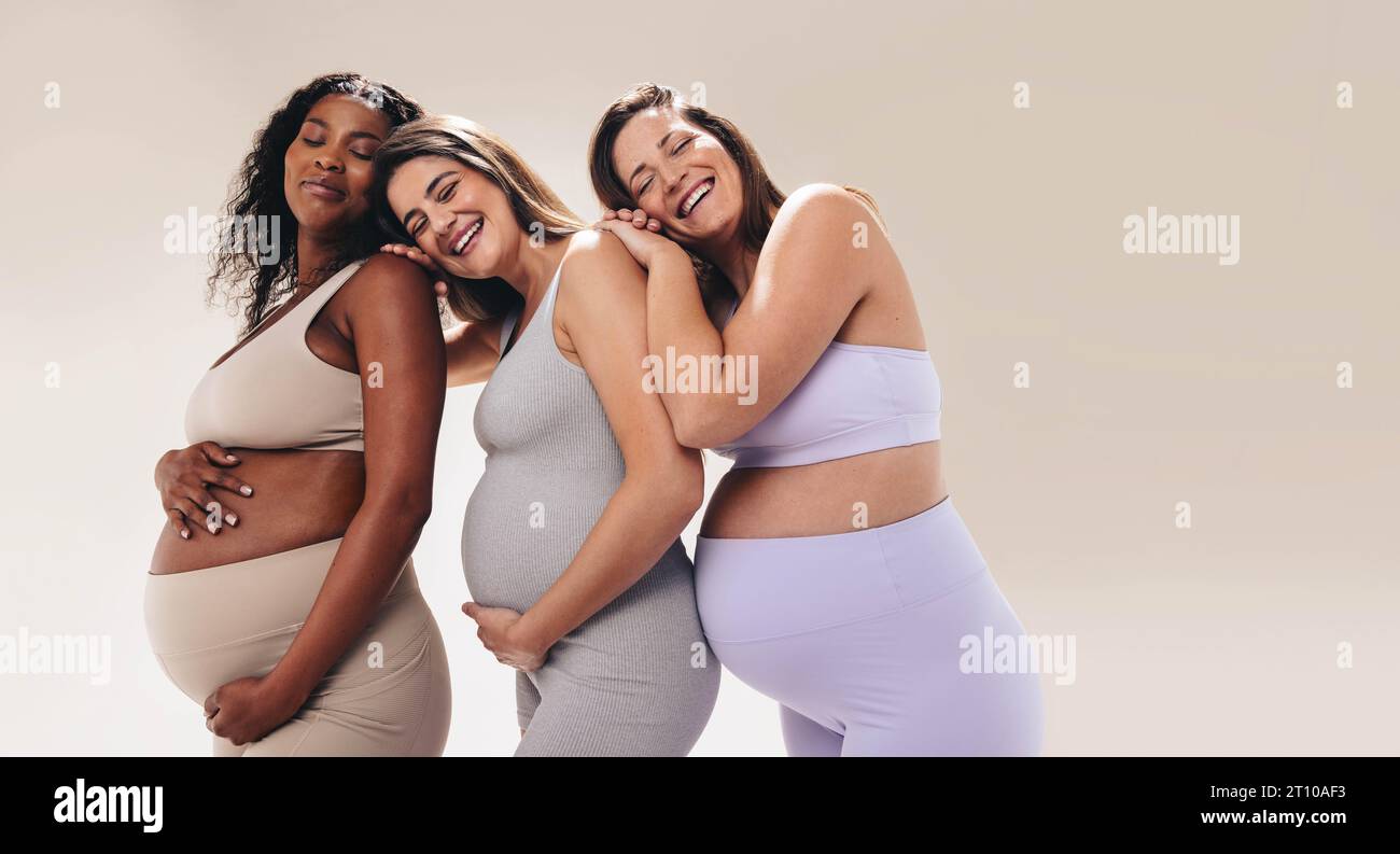Les femmes enceintes multiculturelles vêtues de vêtements de fitness assistent à un cours de yoga prénatal, se penchant les unes sur les autres pour obtenir du soutien. Heureux et souriants, ils priorisent Banque D'Images