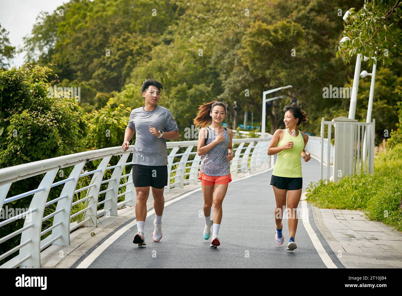 trois jeunes femmes asiatiques joggeurs féminins s'exerçant à l'extérieur ensemble dans le parc de la ville Banque D'Images