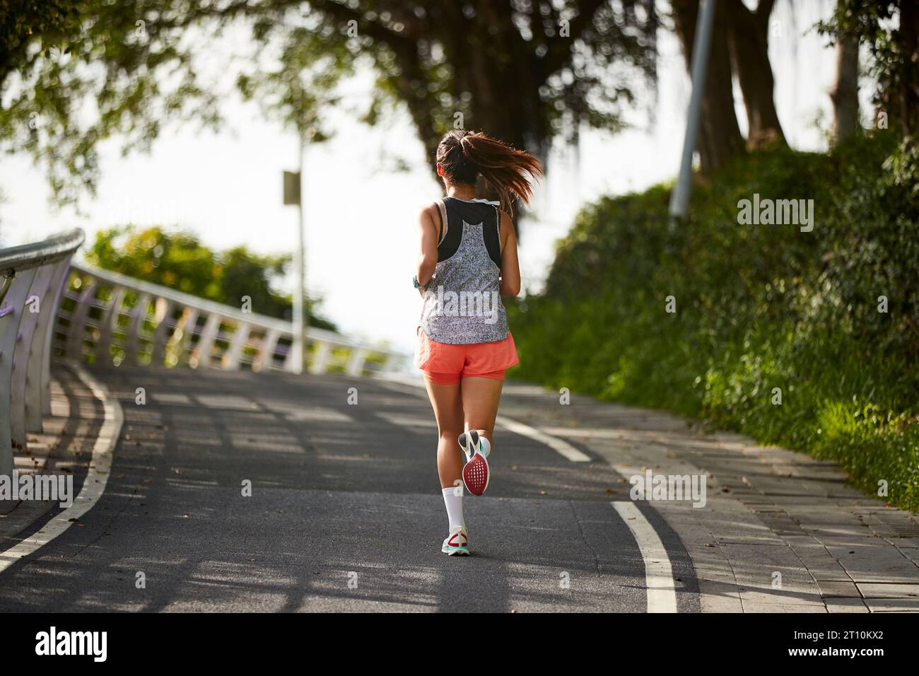 vue arrière de la jeune femme asiatique joggeuse s'exerçant à l'extérieur dans le parc de la ville Banque D'Images