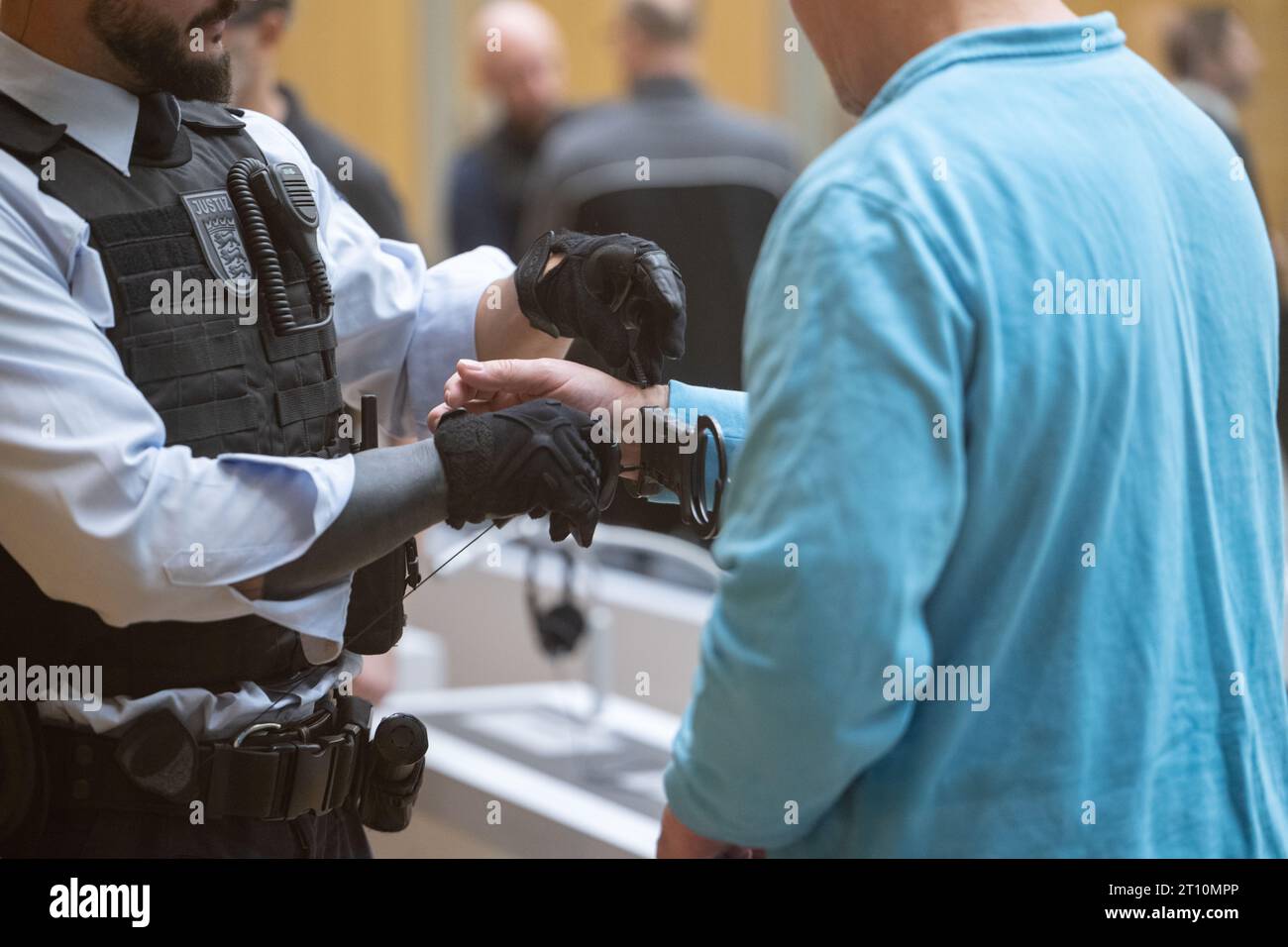 10 octobre 2023, Bade-Württemberg, Stuttgart : un défendeur (r) se fait enlever les menottes dans une salle du tribunal régional supérieur de Stuttgart. Onze accusés doivent répondre de la fondation, de l'appartenance et du soutien du groupe terroriste présumé 'Gruppe S.' devant la haute Cour régionale. Photo : Marijan Murat/dpa Banque D'Images