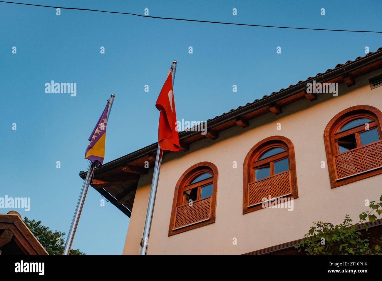 Majestueux bâtiment bosniaque, mélange de tradition et de fierté. Drapeaux bosniaque et turc côte à côte, faisant écho à l'harmonie culturelle et à la résonance historique. Banque D'Images