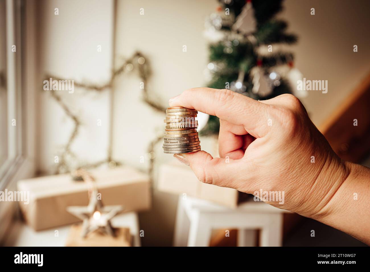 Concept de budget et de finances de Noël. Main de femme tenant de l'argent contre l'arbre de Noël et des ornements à la maison. Banque D'Images