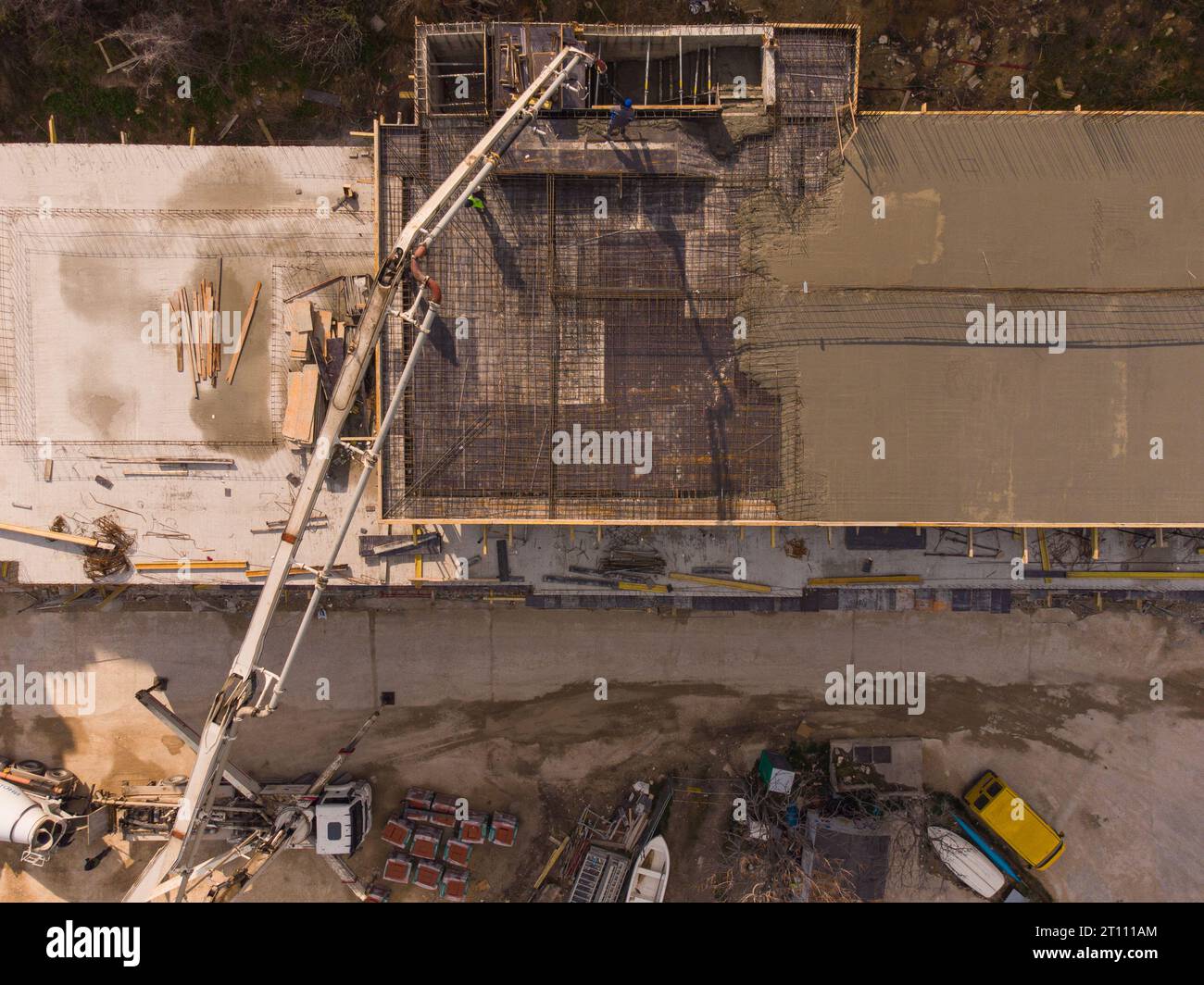 Couler du ciment de béton sur le toit d'un bâtiment résidentiel en construction à l'aide d'une machine de camion de pompe à béton avec flèche haute pour alimenter le mixtur Banque D'Images