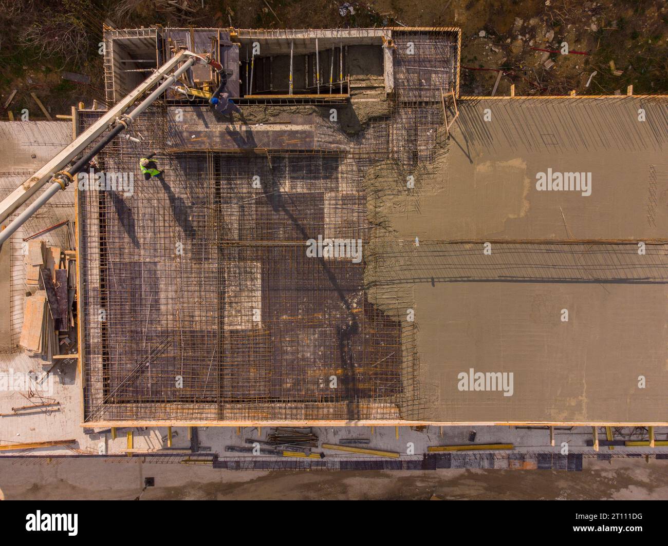 Couler du ciment de béton sur le toit d'un bâtiment résidentiel en construction à l'aide d'une machine de camion de pompe à béton avec flèche haute pour alimenter le mixtur Banque D'Images