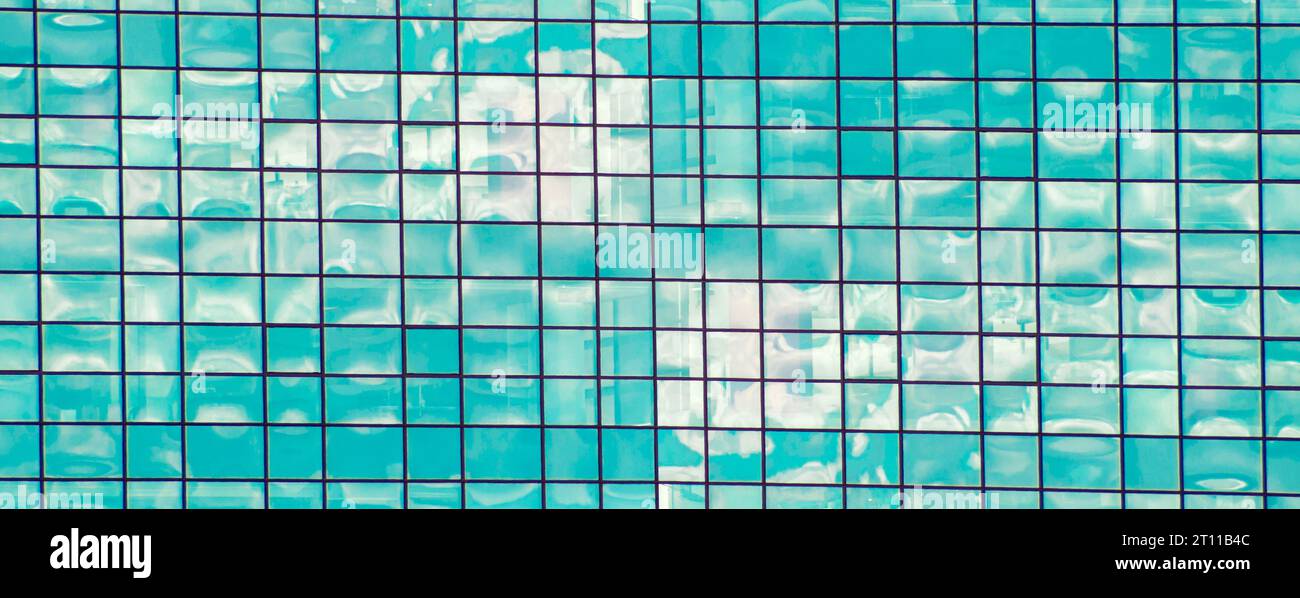 Mosaïque abstraite de carrés dans les tons bleus et blancs. Le ciel bleu avec des nuages blancs se reflète dans le miroir. Intersection de rayures créant un Banque D'Images