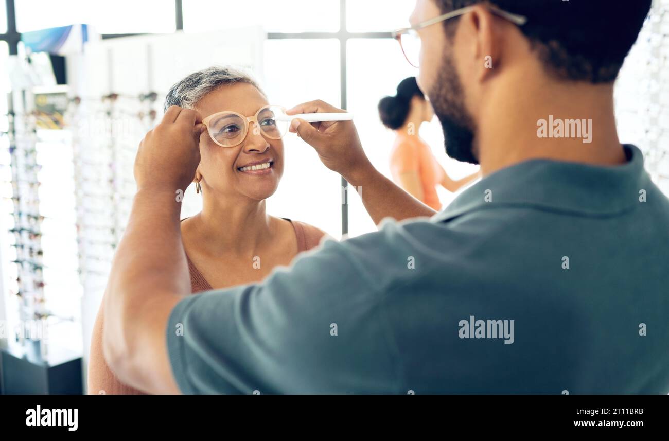 Optométriste, tester les lunettes et mesurer la distance pupillaire de la femme mature pour la lentille de prescription, vérifier ou examiner en magasin. Sourire, opticien ou homme écrivant dessus Banque D'Images
