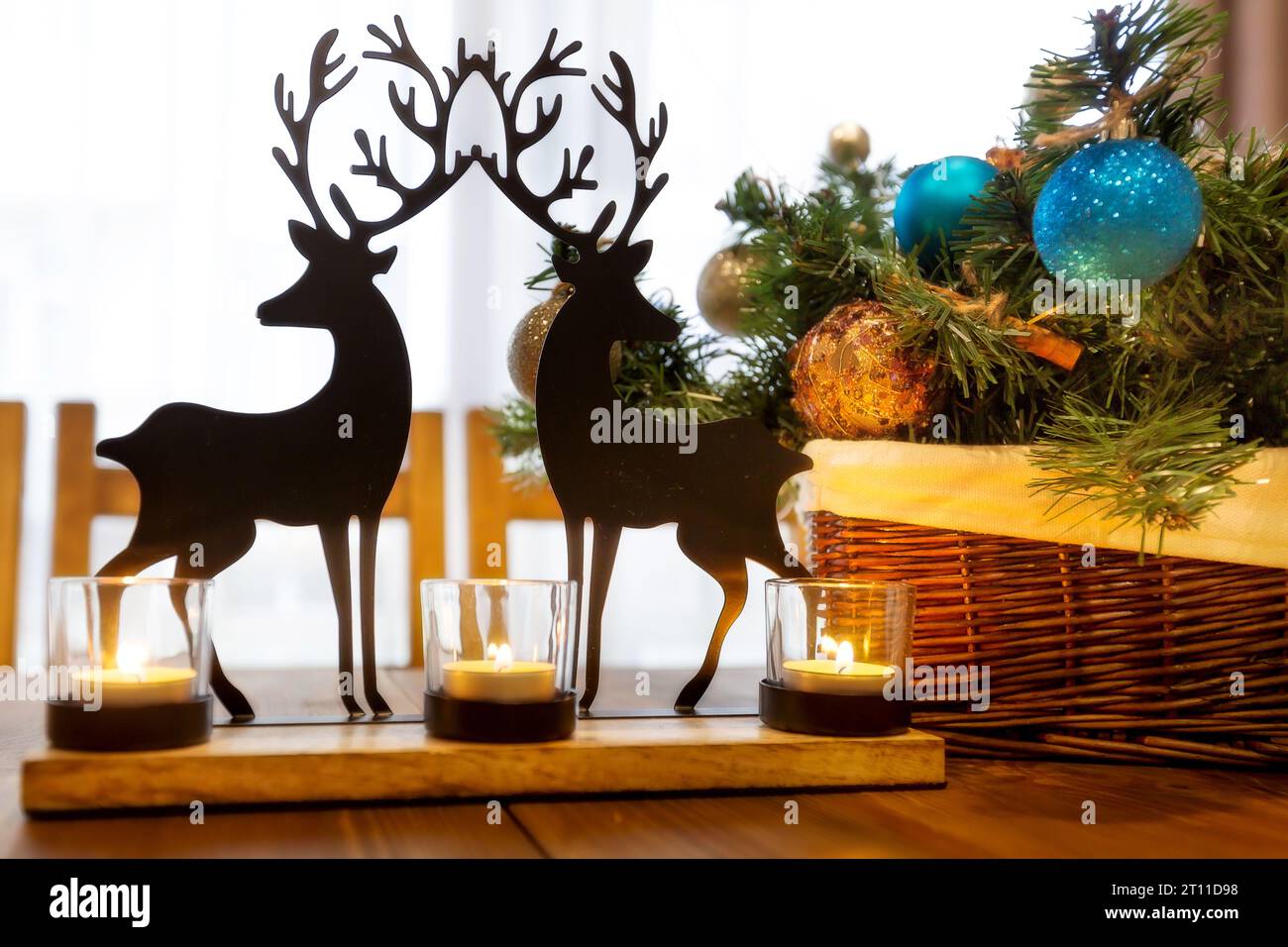 Jouet de noël de renne sur la table en bois, bougies, branche verte, pommes de pin intérieur de vacances Banque D'Images