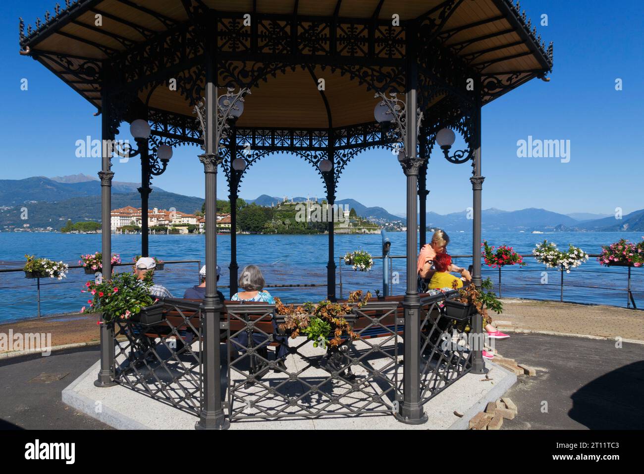 Les gens sont assis sous un belvédère orné par un lac serein avec des montagnes et un ciel bleu en arrière-plan à Stresa, lac majeur, Italie, Europe Banque D'Images