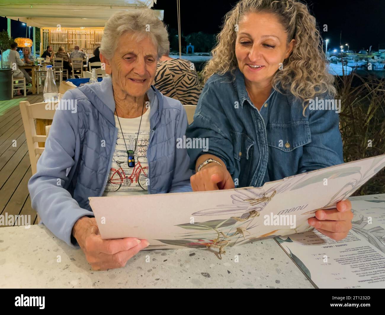 Malia, Crète, Grèce, Europe, 01 OCT 2023. Femmes lisant un menu dans un restaurant grec, Malia, Crète. Banque D'Images