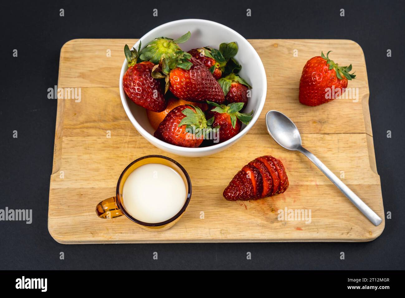 Vue aérienne d'une fraise coupée dans un bois avec une base de lait et un bol blanc avec plus de fraises Banque D'Images