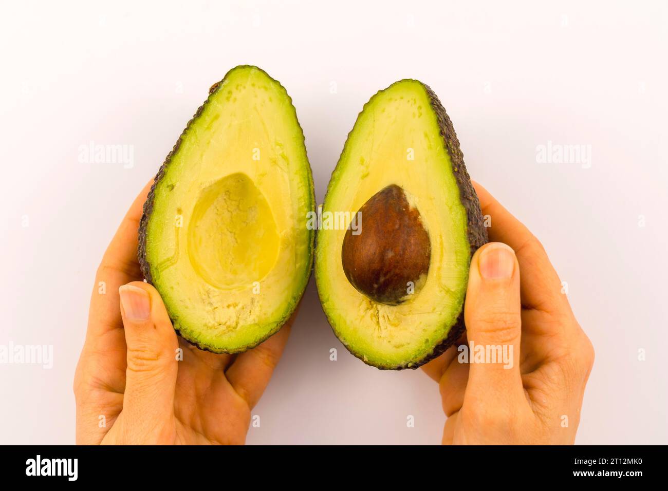 Mains d'une femme séparant l'avocat en deux avec espace copier et coller. Recette pour préparer